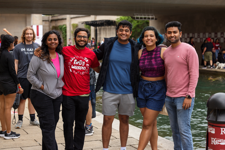 5 Students hugging while looking forwards underneath the White River canal at IU Indianapolis' Regatta.
