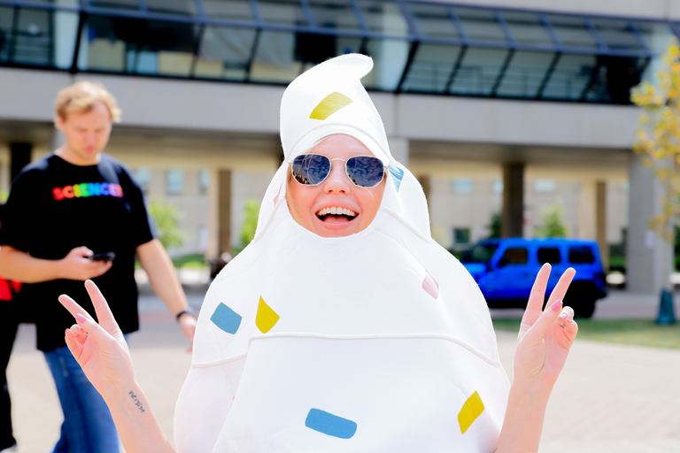 A woman smiling and holding up peace signs with her fingers at the IU Indianapolis Ice Cream Social. She is wearing a white Ice Cream costume.