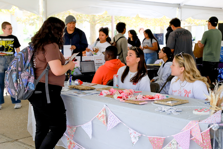 A woman talking to people seated at a table at the Student Involvement Expo at IU Indianapolis.