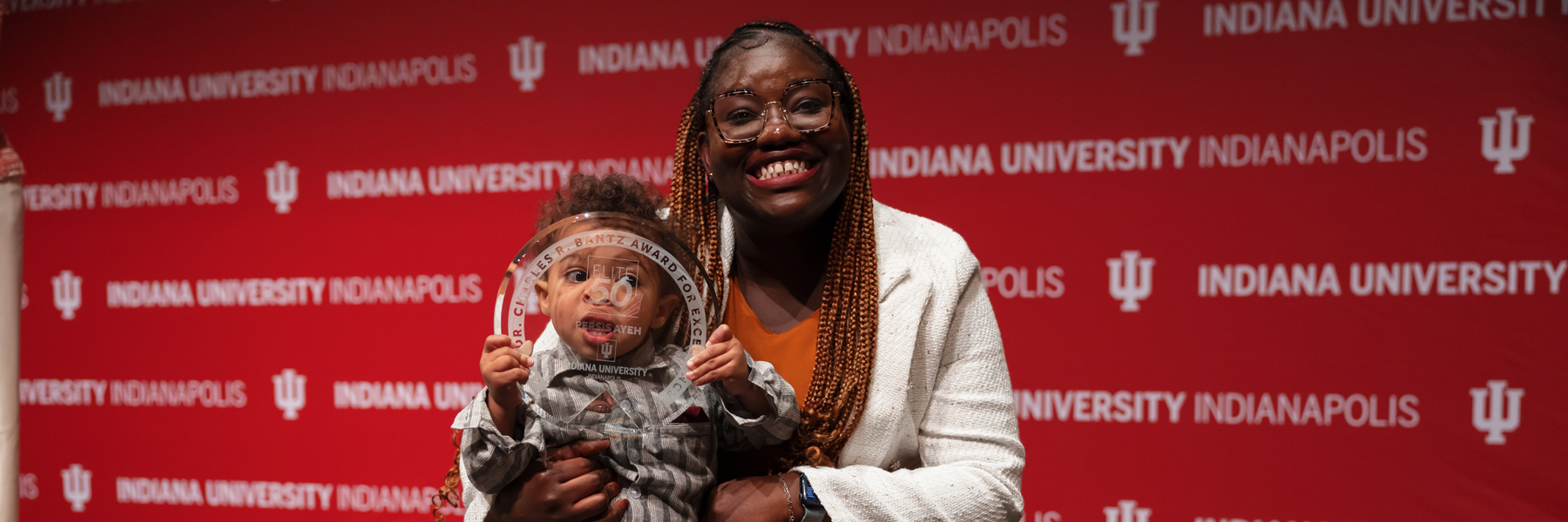A woman standing with her son who holds an award.
